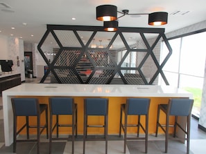 A modern kitchen with a central island, bar stools, and a geometric decorative wall. - GLō Best Western Olive Branch (Olive Branch)