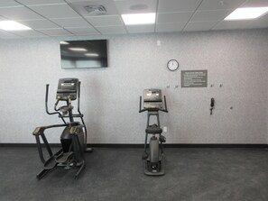 Une salle de sport équipée de deux tapis de course et d’une horloge fixée au mur.