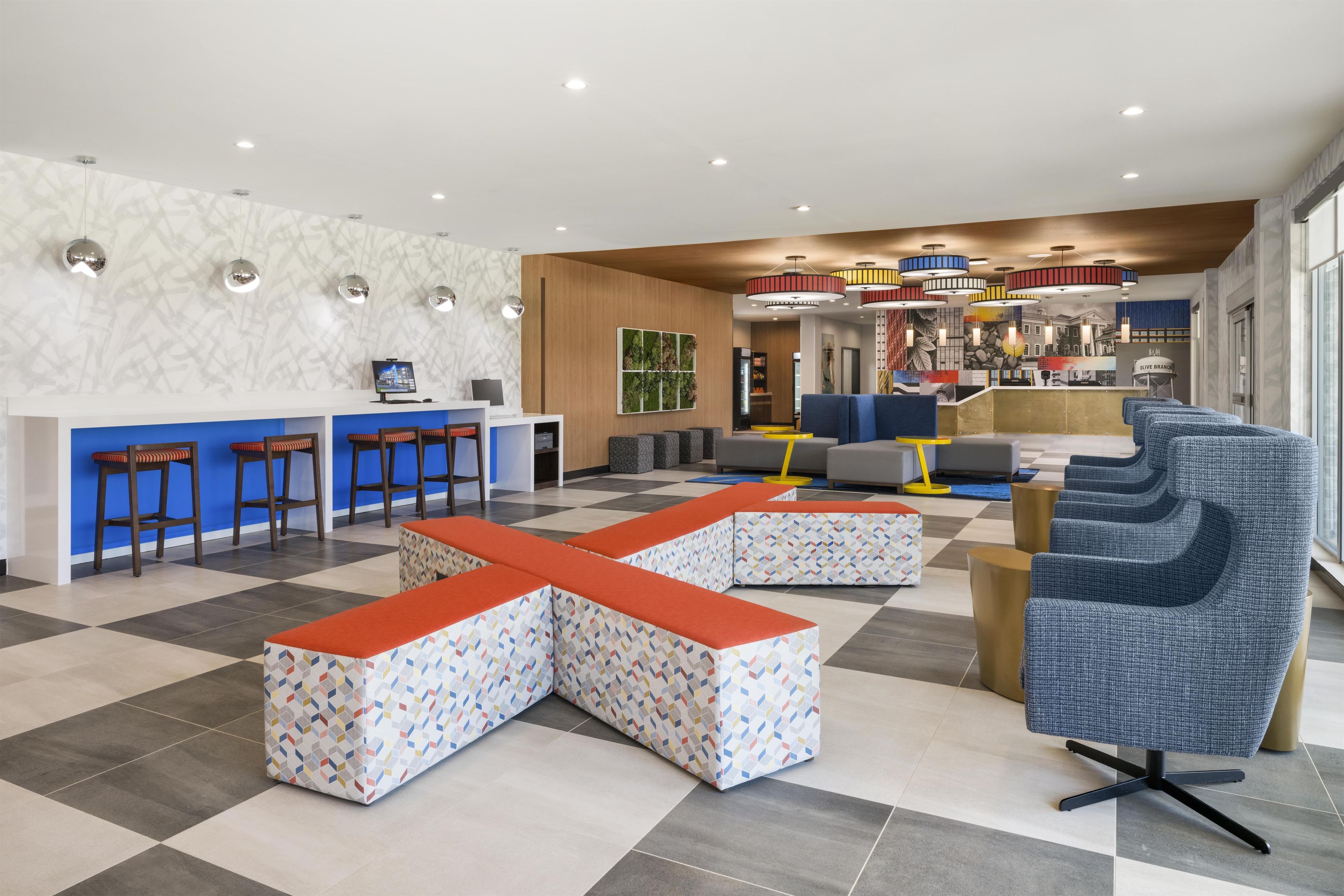 A modern lobby with a checkered floor, seating areas, a reception desk, and a bar.