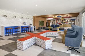 Eine moderne Lobby mit Schachbrettmuster-Bodenbelag, Sitzbereichen, einem Empfangsbereich und einer Bar.