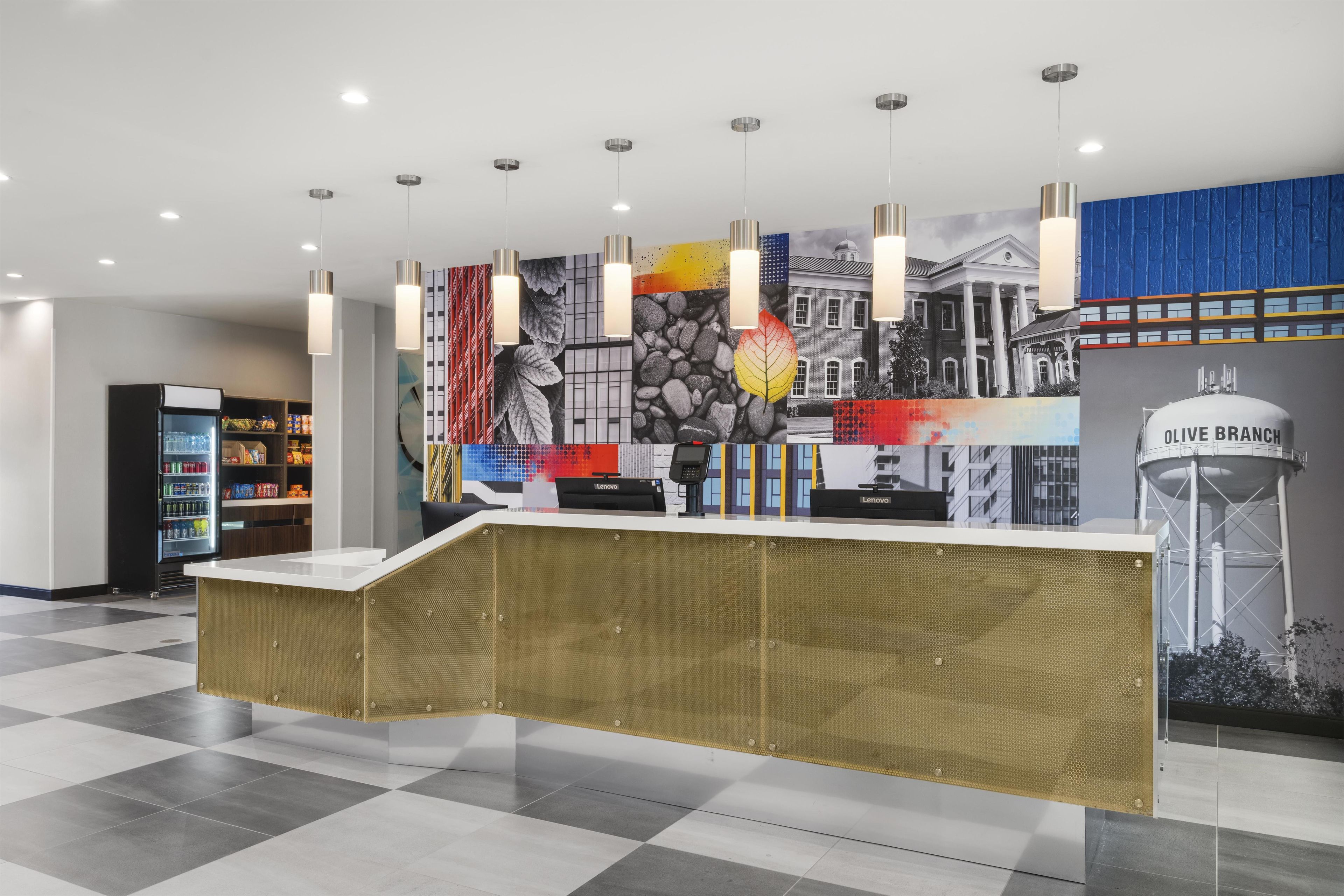 Een receptiebalie met een incheckgedeelte, een automaat en een muur met een stadsgezichtsmural.