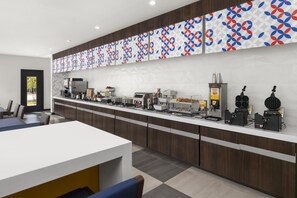 Un bar à petit-déjeuner moderne, doté de divers distributeurs de nourriture et d’un espace détente avec des chaises.