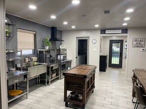 Une cuisine moderne dotée d’appareils électroménagers en acier inoxydable, d’une table en bois et d’une pancarte sur laquelle on peut lire : « DÉTENDEZ-VOUS ET RELÂCHEZ-VOUS ».