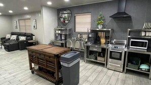 Une cuisine moderne avec un carrelage gris, une table à manger en bois et des appareils électroménagers en acier inoxydable.