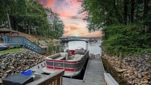 A dock with a boat, wooden deck, and rocky shoreline. - Heated Pool, Hot Tub, Game Rm, Boat Dock, Lakefront Views (Lake Norman of Catawba)