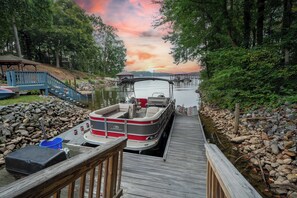 Un quai avec un bateau, une terrasse en bois et une rive rocheuse.