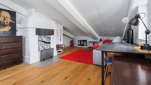 Una habitación estilo loft con techo alto, pared de ladrillo visto y piso de madera, además de una alfombra roja.