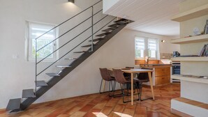 Une cuisine moderne avec un escalier noir, une table à manger en bois et des chaises.