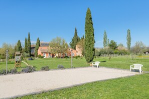 Ein Park mit Sandfläche, Bänken und einem Gebäude mit rotem Dach.