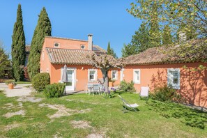 Ein Haus mit einem Ziegeldach, einem Garten mit Rasen und einem Baum.