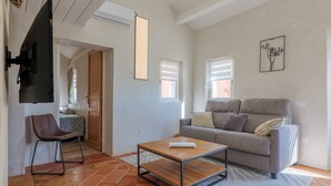 Un salon avec un canapé, une table basse, un fauteuil et un téléviseur.