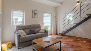 Un salon avec un canapé, une table basse, un sac jaune et un escalier.