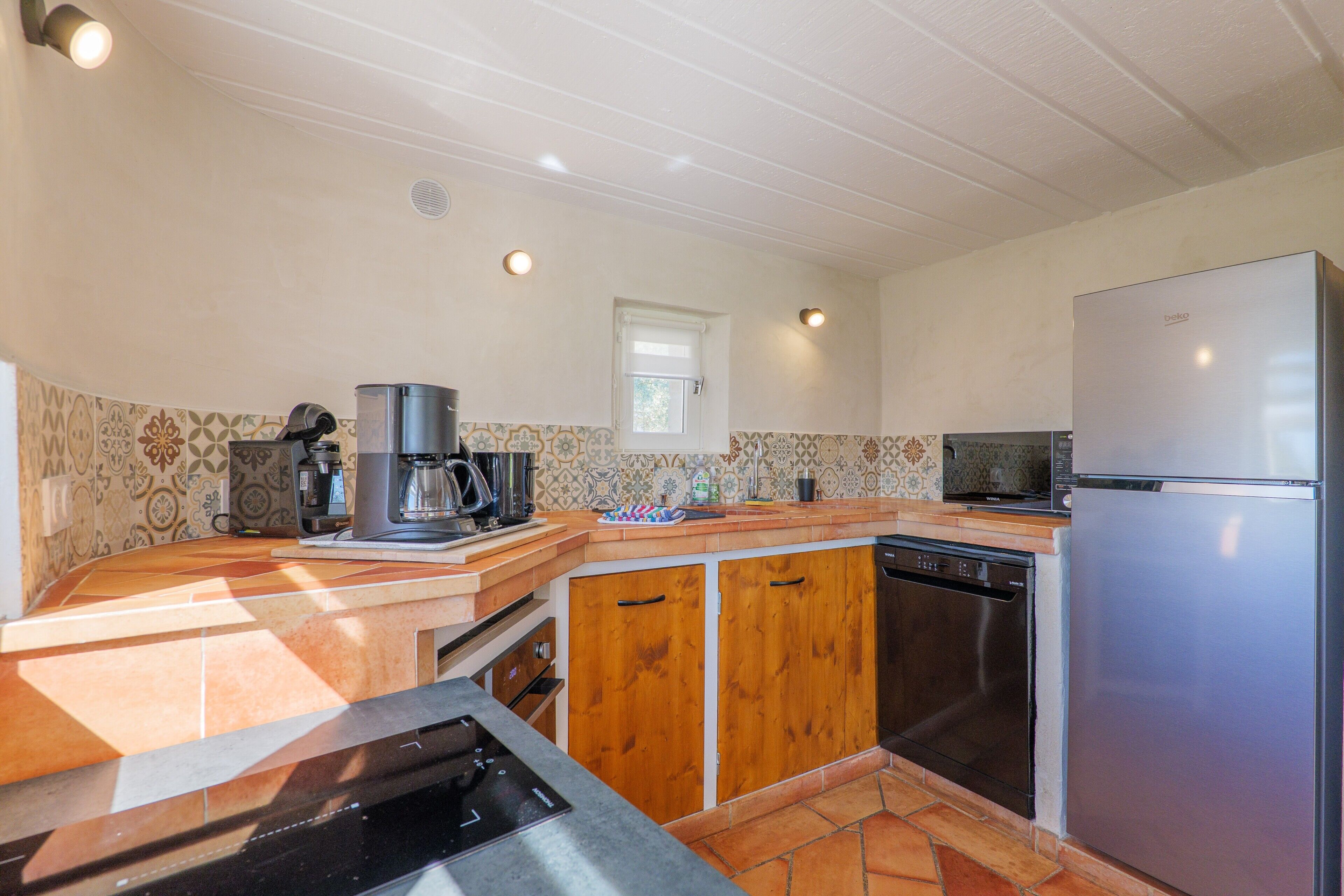 A kitchen with a built-in oven, a coffee maker, a microwave, and a refrigerator.
