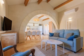 A living room with a sofa, a TV, and a dining area with chairs and a table.