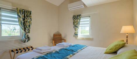 A bedroom with a bed, a chair, a window, and a lamp.
