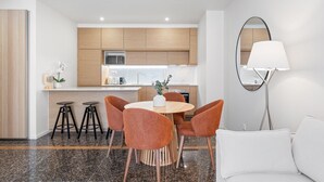 Eine moderne Küche mit Holzausziehtischen, einer Mikrowelle und einem Essbereich mit rundem Tisch und orangefarbenen Stühlen.