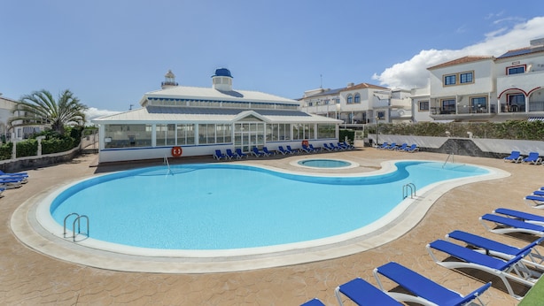 En swimmingpool med solstolar, ett överbyggt område och en byggnad med ett kupoltak.