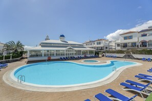 A swimming pool with lounge chairs, a covered area, and a building with a dome roof.