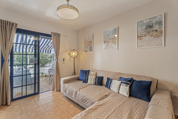 A room with a large bed, a ceiling fan, and a view through a glass door to an outdoor area.
