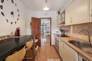 A kitchen with a black countertop, yellow chairs, a coffee machine, and a sink.