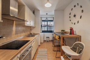 A modern kitchen with a stove, sink, and a dining area with chairs and a table.