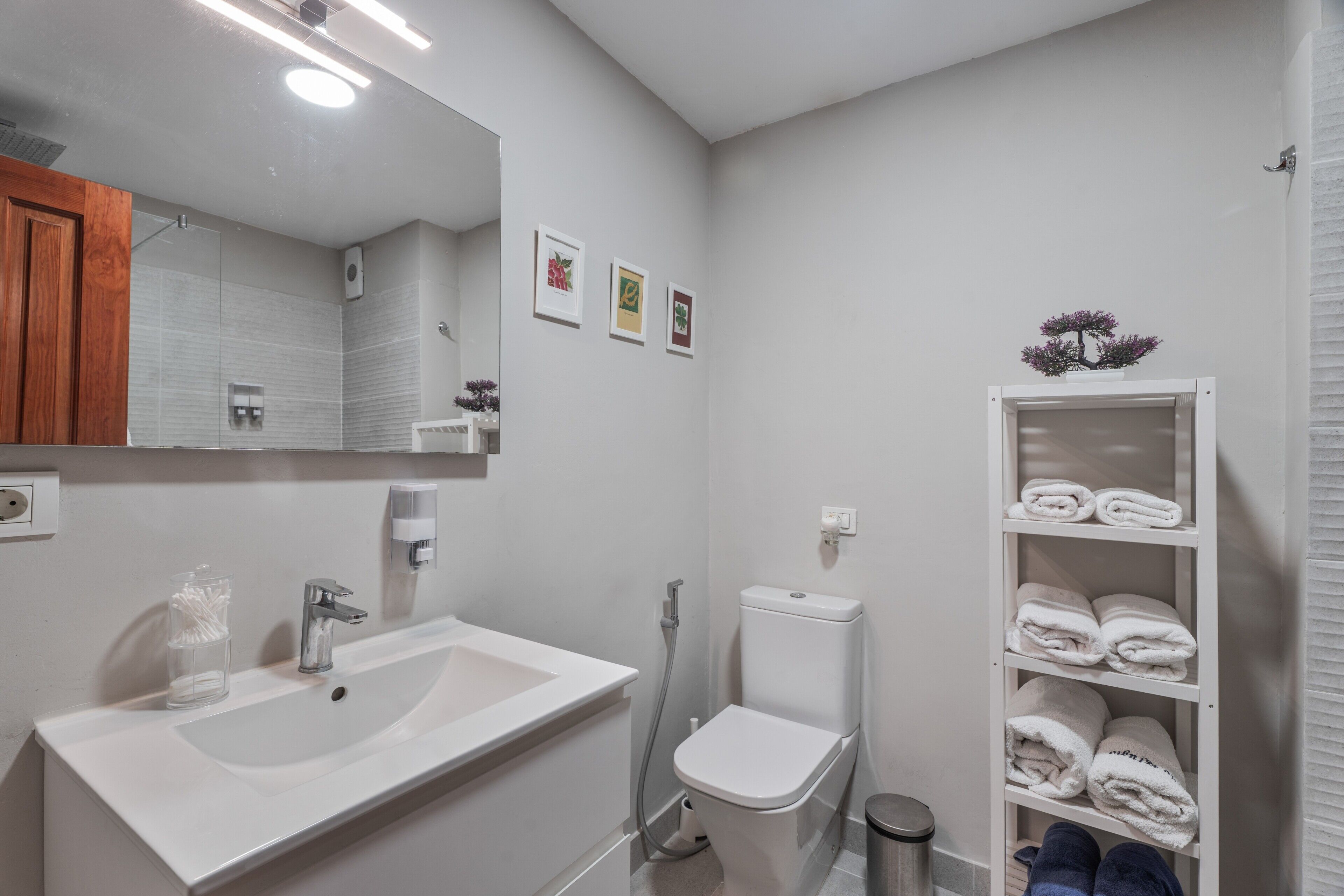 A modern bathroom with a sink, mirror, toilet, and towel rack.