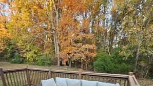 A wooden deck with a sectional sofa and a fire pit.