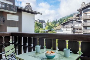 A balcony with a table, two chairs, a bowl of snacks, and two mugs. - Bright and practical in the heart of Chamonix (Chamonix-Mont-Blanc)