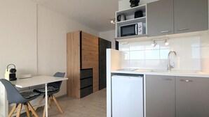 A compact kitchen with a microwave, sink, and storage cabinets.
