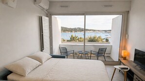 A bedroom with a bed, a TV, a desk, and a balcony with a view.