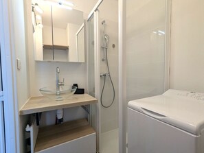 A bathroom with a glass sink, a mirror, a shower, and a white toilet.