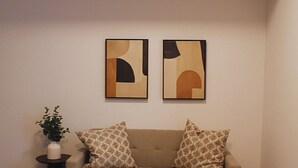 Una sala de estar con un sofá color crema, cojines estampados y arte abstracto en la pared.