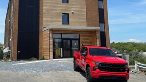 Un edificio moderno con una camioneta roja estacionada frente a él.