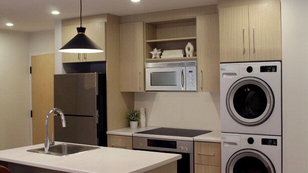 Una cocina moderna con una isla central, microondas, lavadora y un fregadero.