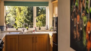 Een keuken met houten kastjes, een gootsteen en een raam met uitzicht op bomen.