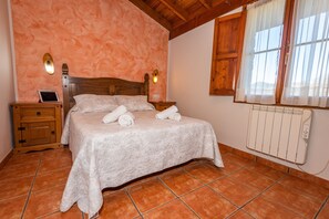 Une chambre à coucher avec un lit, des tables de chevet, une tablette, un radiateur et une fenêtre avec des rideaux.