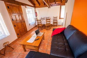 Um quarto com uma mesa de madeira, um sofá de couro preto, uma área de refeições com cadeiras e uma porta de madeira.