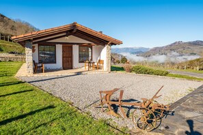 Un bâtiment rustique en pierre, doté d’un toit en bois, d’une terrasse en gravier et d’un vélo.