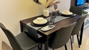 Un espace repas moderne avec une table en bois foncé, des chaises à revêtement gris et un grand miroir rond accroché au mur.