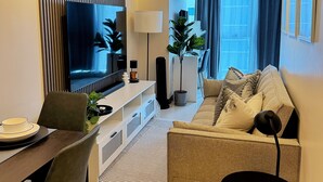 Un salon moderne équipé d’un téléviseur à écran plat, d’un canapé, d’une table à manger et de chaises.