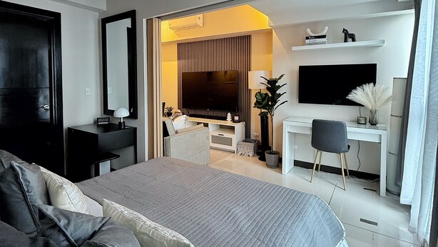 Une chambre d’hôtel moderne équipée d’un grand lit, d’un bureau, d’une télévision et d’un coin salon.