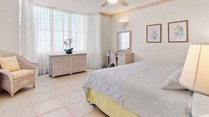 Ein Schlafzimmer mit Bett, Kommode, Sessel, Schreibtisch und Deckenventilator.