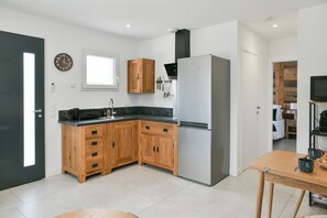 Une cuisine moderne avec des meubles en bois, un réfrigérateur en acier inoxydable et une fenêtre.