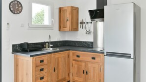 Una cucina con mobili in legno, un frigorifero in acciaio inossidabile, una sveglia e una finestra.