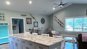 A kitchen with a granite countertop, grey cabinets, and a blue and white checkered rug. - 2 BR Retreat by the waterfront in 
Little River, SC (Little River)