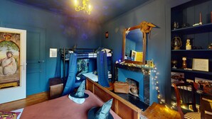 Una habitación con literas, chimenea, un espejo y estantes con diversos objetos.