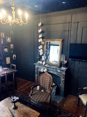 A room with a chandelier, a fireplace, a mirror, and a television.