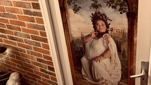 Una puerta con un escudo de armas y un cuadro clásico de una mujer con vestido.