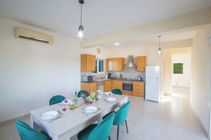 A modern kitchen with wooden cabinets, a white refrigerator, and a dining area with a table set for two.