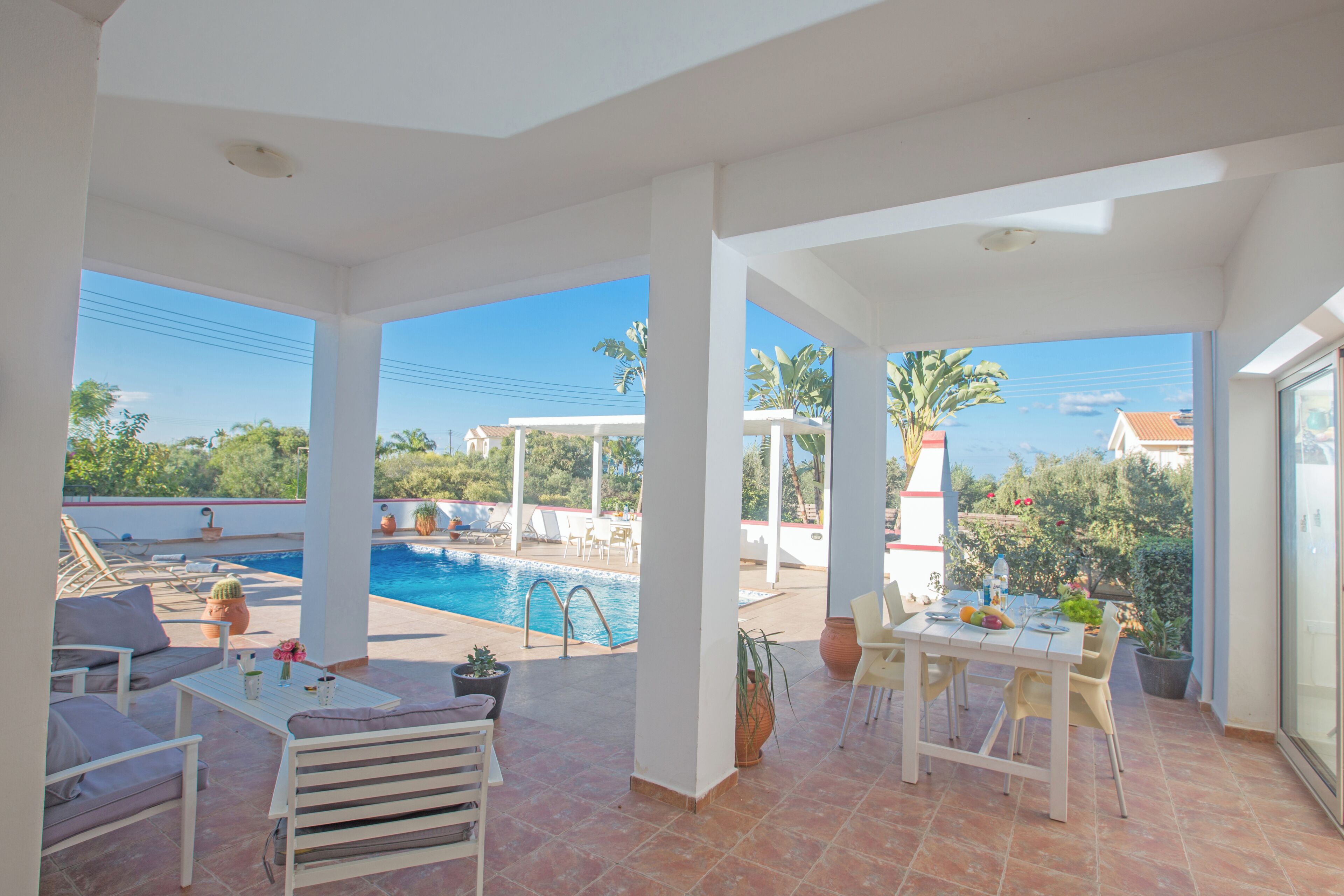 A spacious outdoor area with a pool, seating, and a table with chairs.